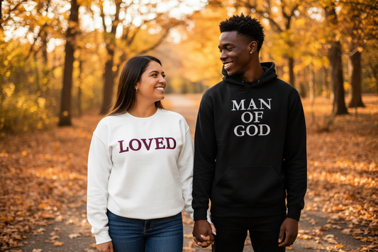 Couple holding hands in fall setting wearing LOVED crewneck and MAN OF GOD hoodie